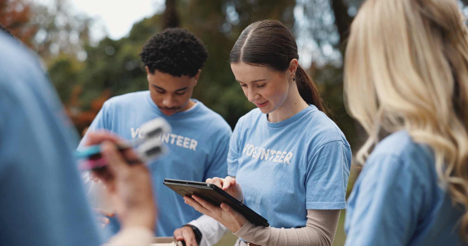 Volunteers looking up information on a tablet at an outdoor event.