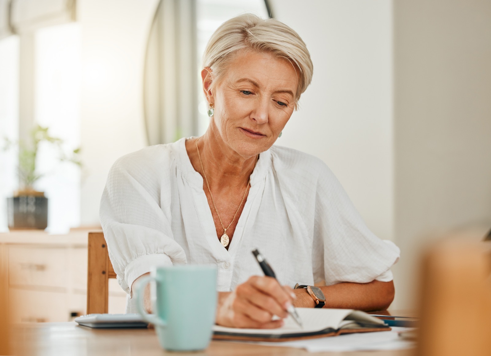 Woman writing in a notebook at a table.