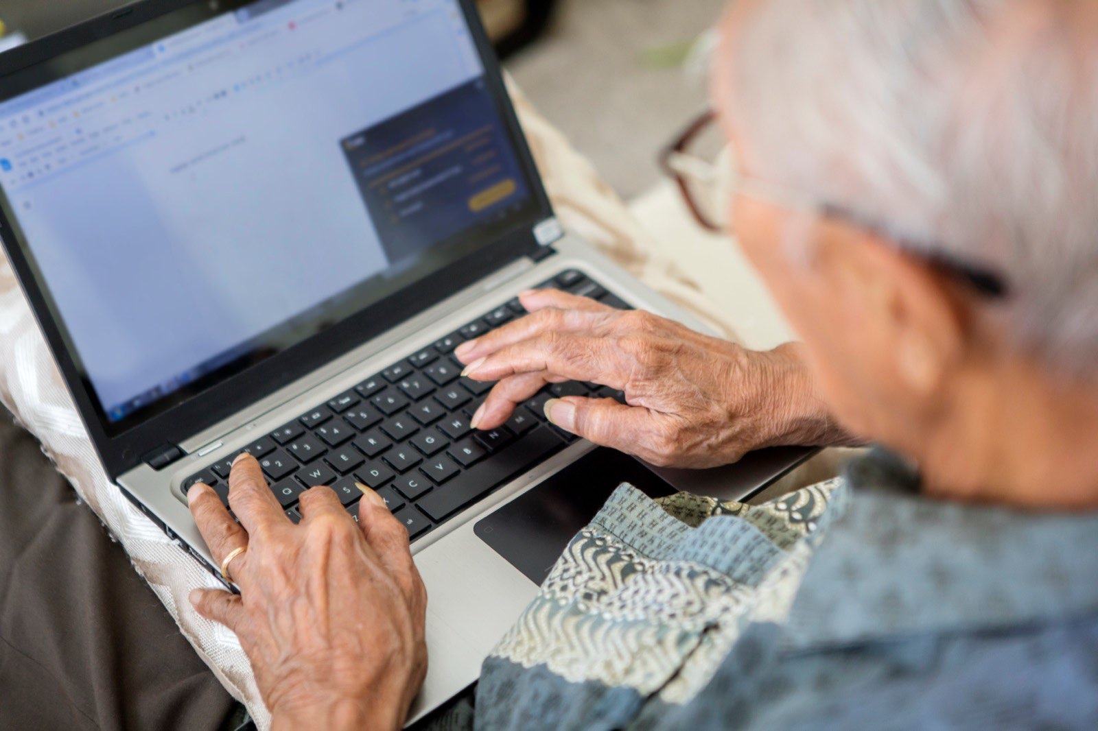Older gentleman sitting at home working on a laptop.