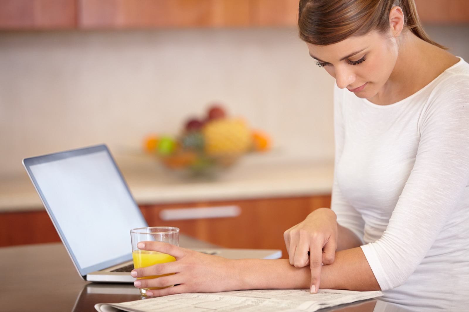 Woman sitting at a table, with open laptop, and notes on paper.
