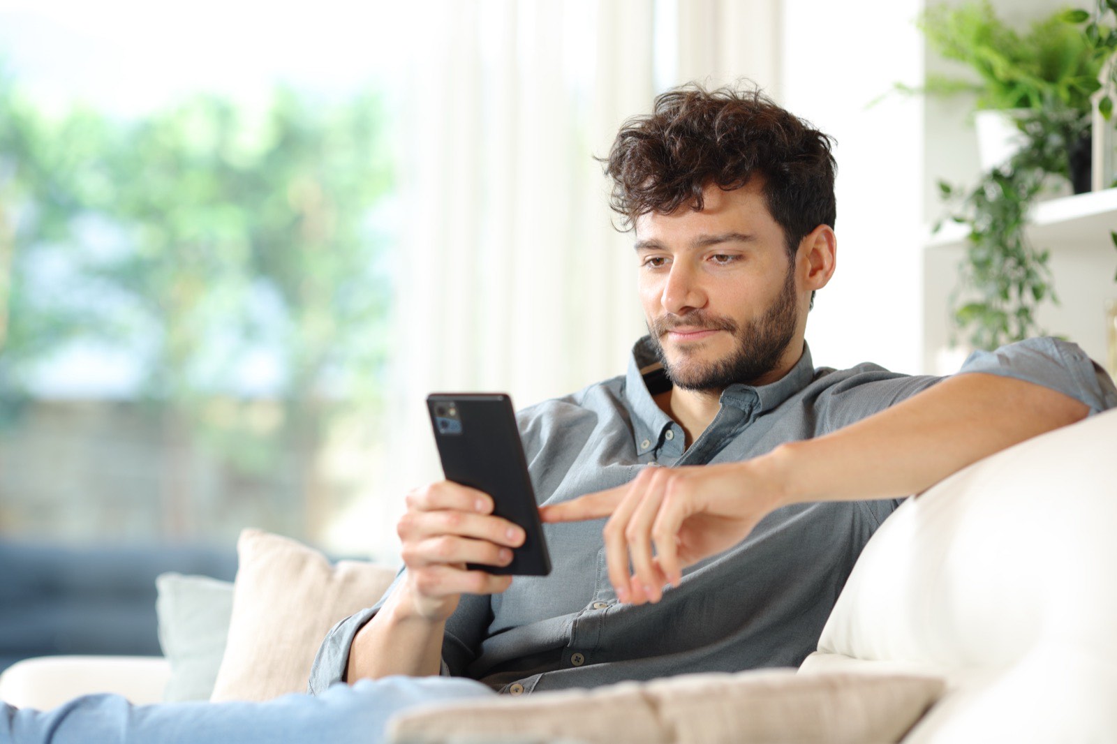 Man relaxing on couch, reading his phone.