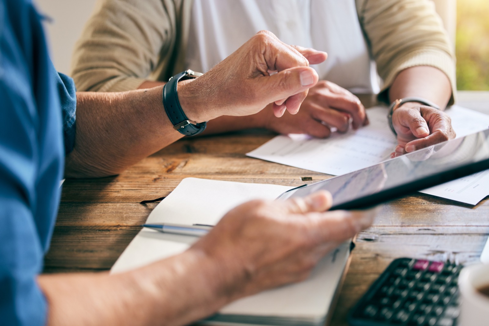 Two people at a wooden table reviewing a printed document together, one pointing to the page.