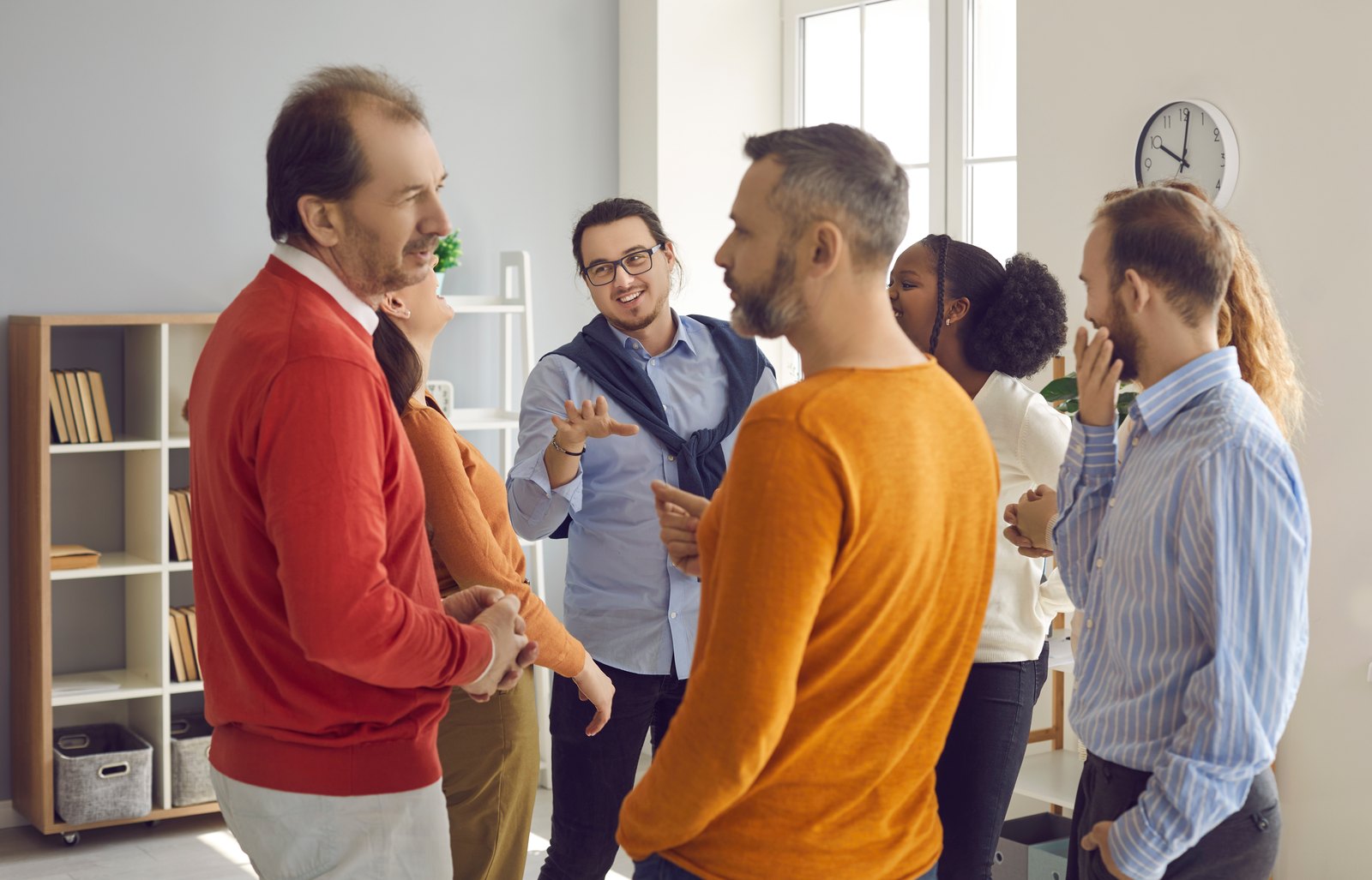 A group of club members standing in a room, talking together in an animated conversation.