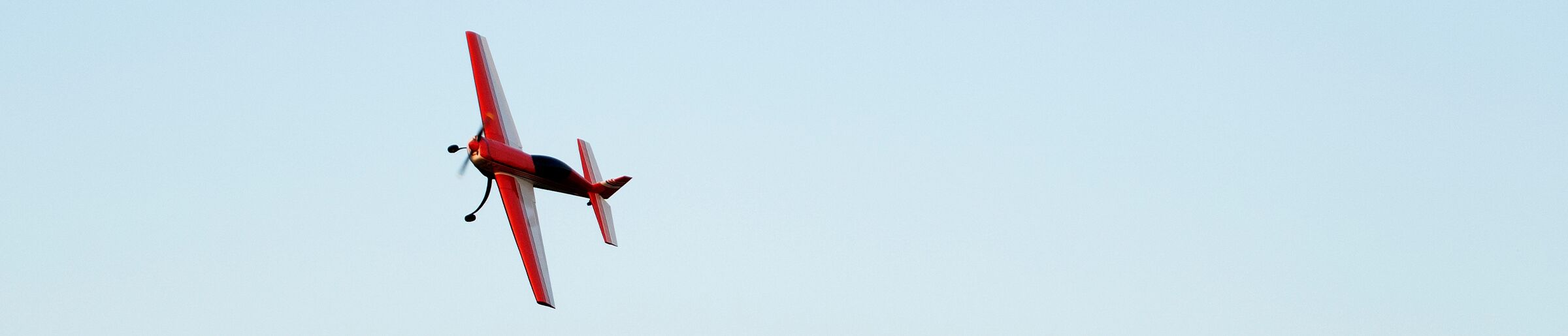 A radio-control model airplane in flight against a clear sky, representing the flying, scale, and glider clubs that run on Clubistry.